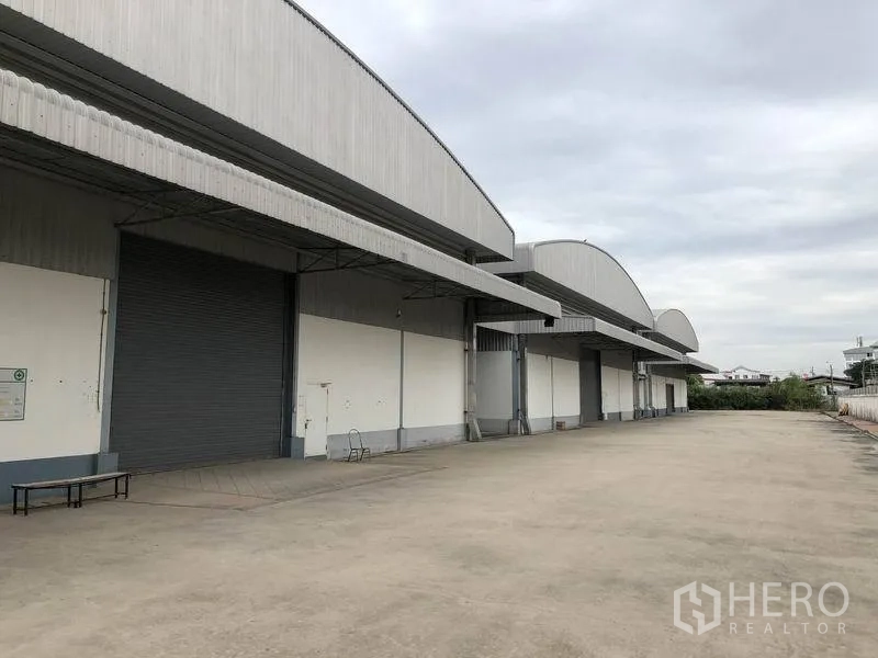 คลังสินค้า ให้เช่าในBang Phli, Samut Prakan - ด้านหน้าโกดังพร้อมช่องโหลดสินค้าหลายจุด ประตูม้วน และลานคอนกรีตกว้างสำหรับรถบรรทุก ในบางพลี สมุทรปราการ
