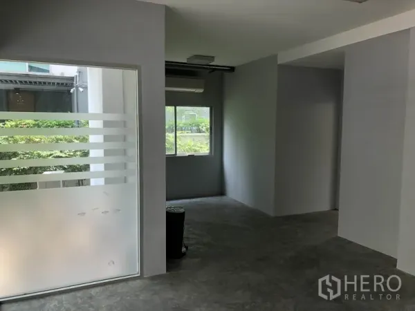 Home Office for rent in Wang Thonglang, Bangkok - Open office room with a frosted glass partition, window air conditioner, and natural light.
