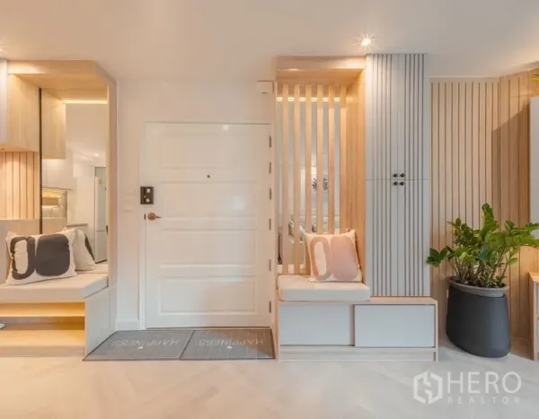 Condominium for sale in Yan Nawa, Bangkok - Entryway with white door, wood-slat accents, built-in bench seating, and indoor plant for a welcoming foyer.