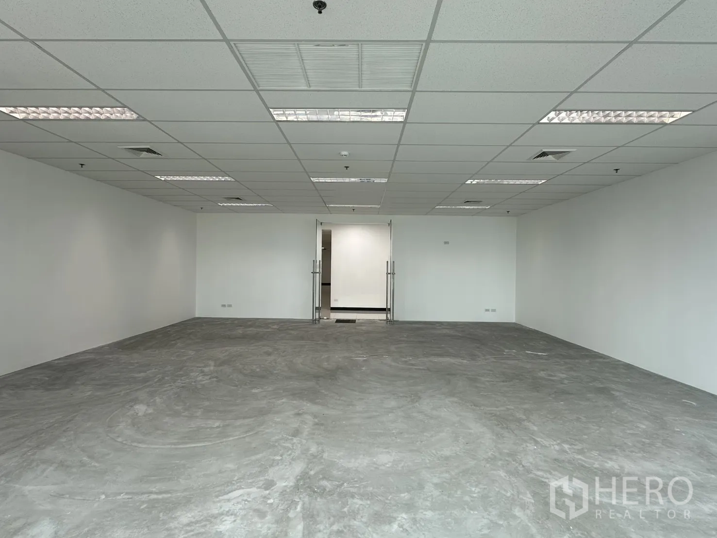 ออฟฟิศ for rent in Watthana, Bangkok - พื้นที่ทำงานโล่งหันไปทางประตูกระจกคู่ พร้อมโคมไฟเพดานและพื้นคอนกรีตขัดมัน.