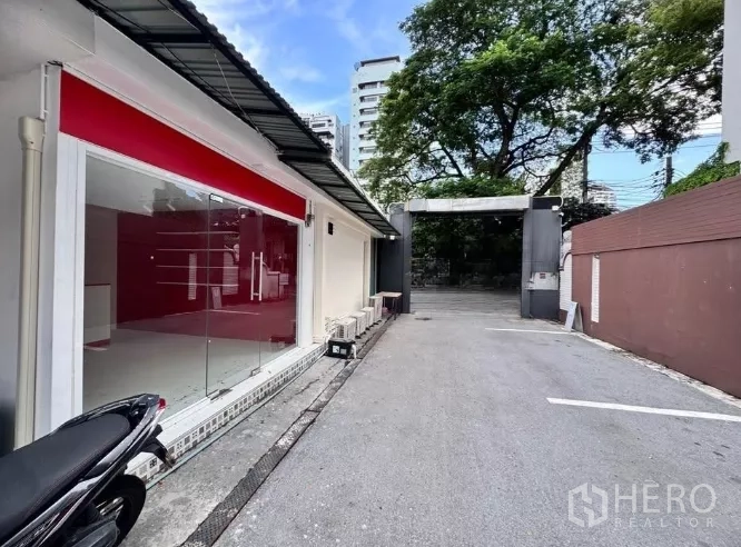 零售空间 出租在Watthana, Bangkok - 瓦他那区通罗一带临街商铺，整面玻璃门面与带门禁的车道入口。