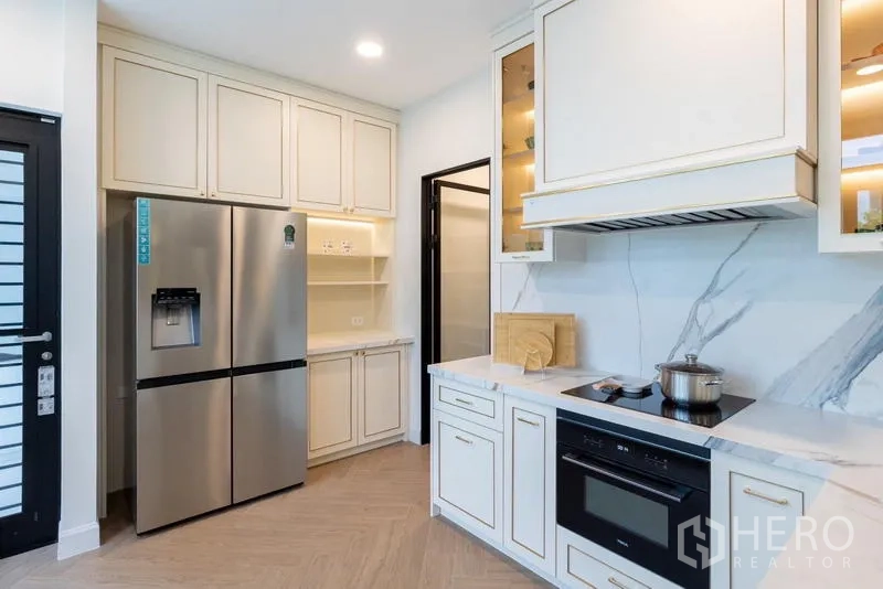 Detached House for sale in Saphan Sung, Bangkok - Modern kitchen with cream cabinetry, stainless refrigerator and marble backsplash.