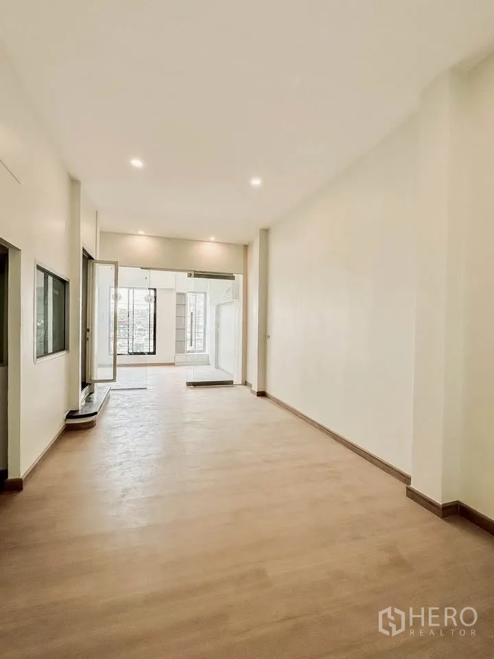 联排别墅 for sale in Wang Thonglang, Bangkok - 长形开放空间，木地板与筒灯通向玻璃门。