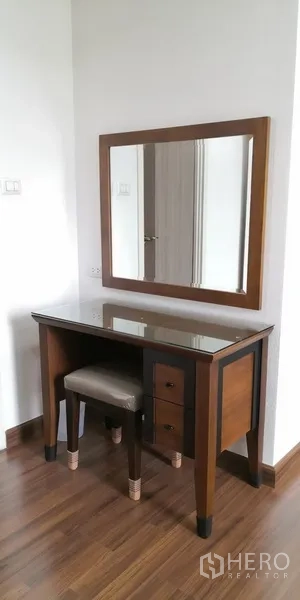 Condominium for rent in Sathon, Bangkok - Wooden vanity with large mirror and stool set against a white wall.
