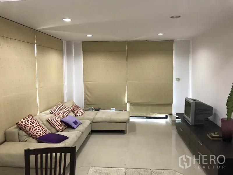 สำนักงานที่บ้าน ให้เช่าในWang Thonglang, Bangkok - ห้องนั่งเล่นพร้อมโซฟาเข้ามุม ตู้วางทีวี พื้นกระเบื้อง และม่านม้วนบานใหญ่