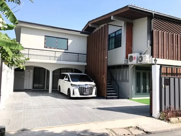 Detached House for rent in Chatuchak, Bangkok - Modern two‑storey detached house exterior with wide tiled driveway, vertical wood slat facade, balcony, and external staircase.