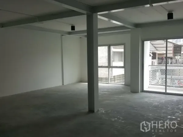 Home Office for rent in Khlong Toei, Bangkok - Bright upper-floor workspace with corner windows and a sliding balcony door.