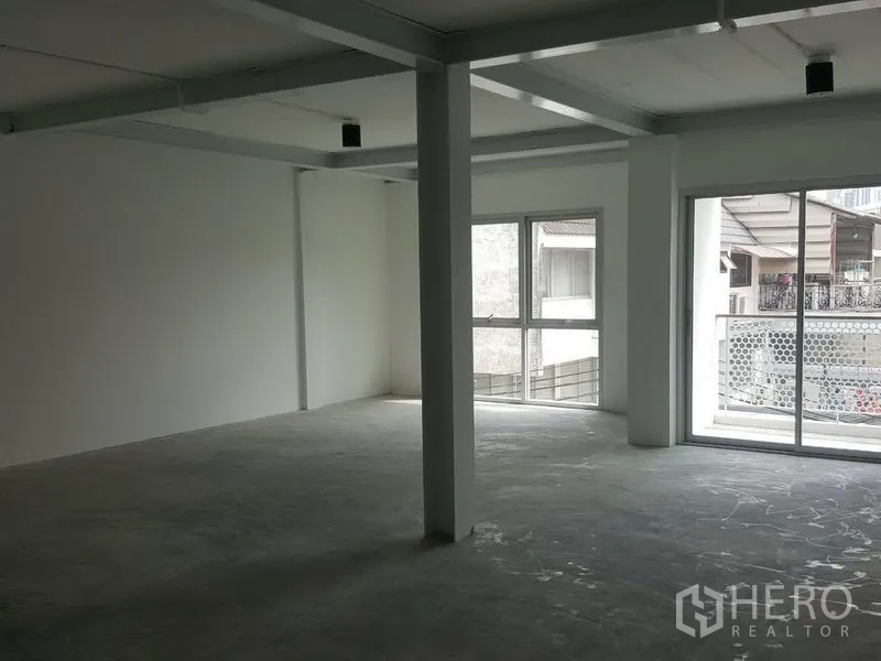 Home Office for rent in Khlong Toei, Bangkok - Bright upper-floor workspace with corner windows and a sliding balcony door.