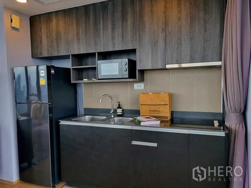 公寓 出租在Bang Rak, Bangkok - 现代小厨房，深色柜体、双槽水池、微波炉与冰箱。