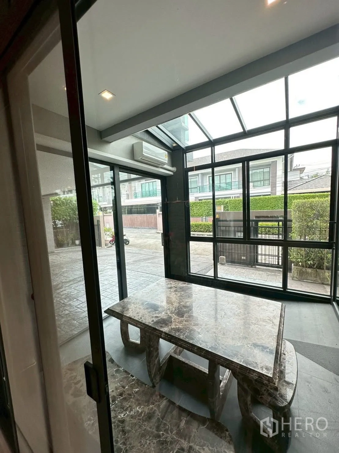 Detached House for sale in Bang Lamung, Chon Buri - Enclosed glass terrace with marble table opening to the driveway.