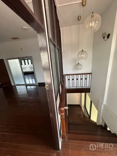 Detached House for rent in Phaya Thai, Bangkok - Staircase landing with wooden handrail and hanging globe pendant lights.