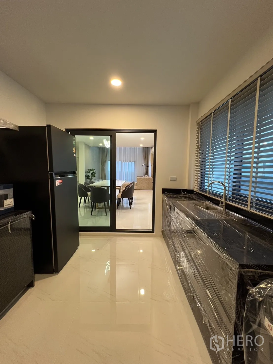 Detached House for rent or sale in Bang Phli, Samut Prakan - Kitchen view to dining through glass sliding door with long counter and sink.