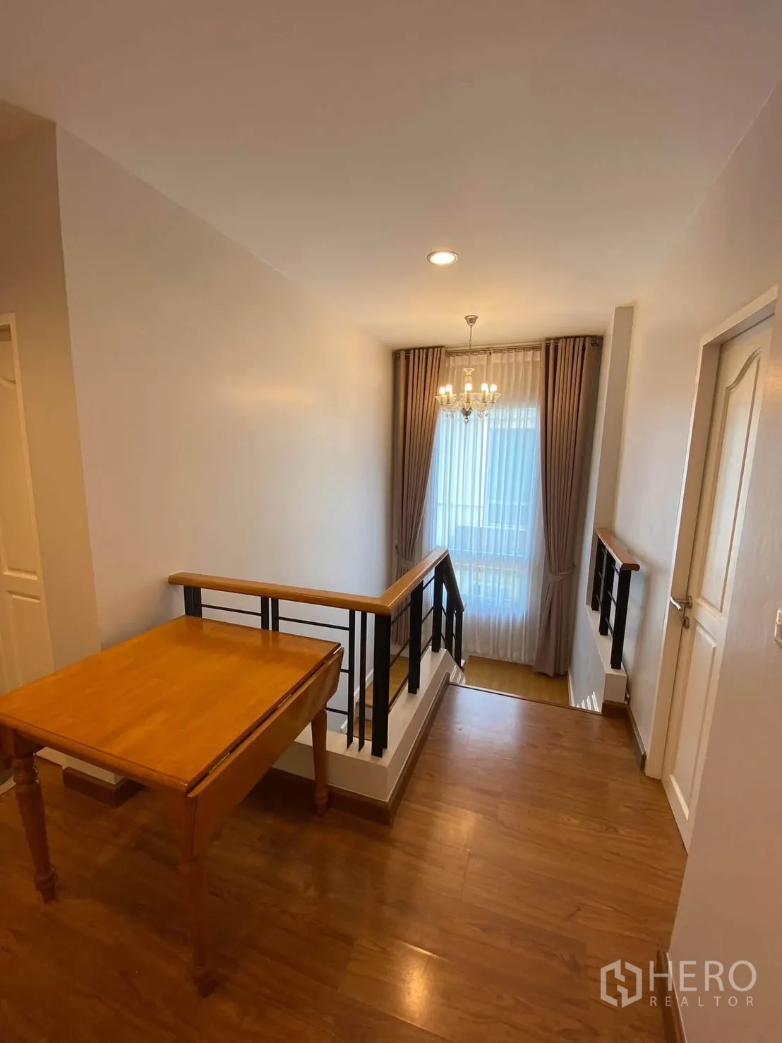 Detached House for rent in Mueang Samut Prakan, Samut Prakan - Upstairs landing with chandelier and wood flooring by the staircase.