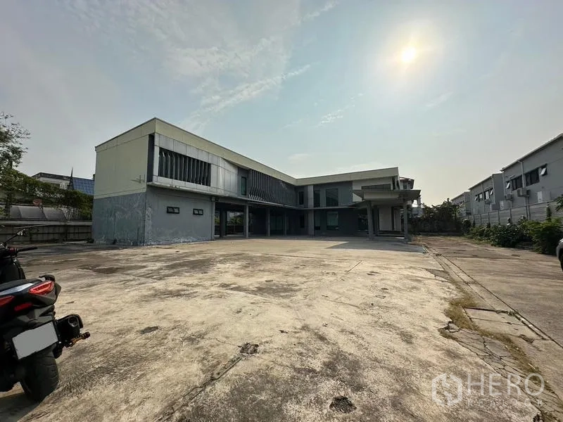 货栈 出租在Prawet, Bangkok - 两层办公仓库外观，宽阔混凝土装卸与停车前院