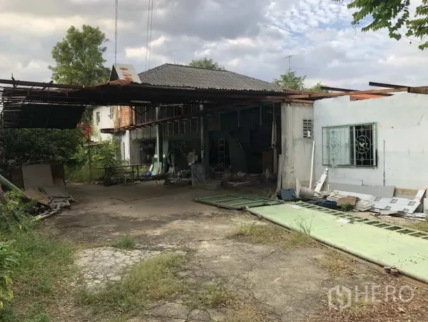 货栈 出租在Sai Mai, Bangkok - 旧仓库外观，波纹铁皮屋顶，开阔院坝与开裂的混凝土车道。