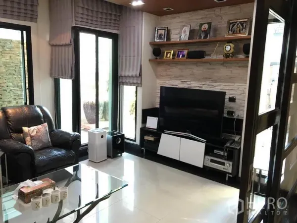 Detached House for rent in Khlong Toei, Bangkok - Cozy TV lounge with leather armchair, media console and shelving by floor-to-ceiling windows.