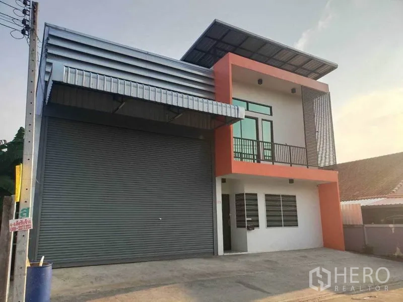 Warehouse for rent in Lam Luk Ka, Pathum Thani - Street-facing warehouse with large roller shutter and second-floor balcony.