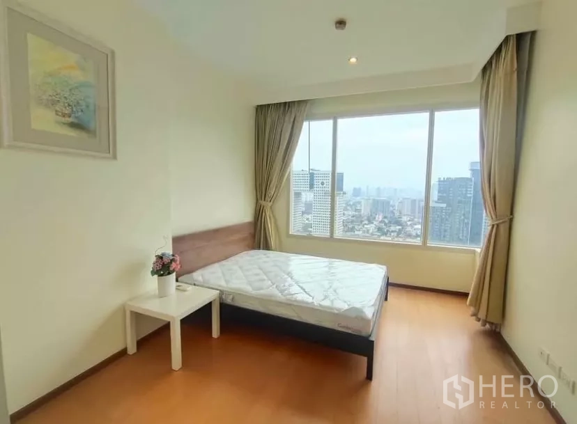 Condominium for rent in Chatuchak, Bangkok - Sunny bedroom with large windows, fitted bed and skyline outlook.