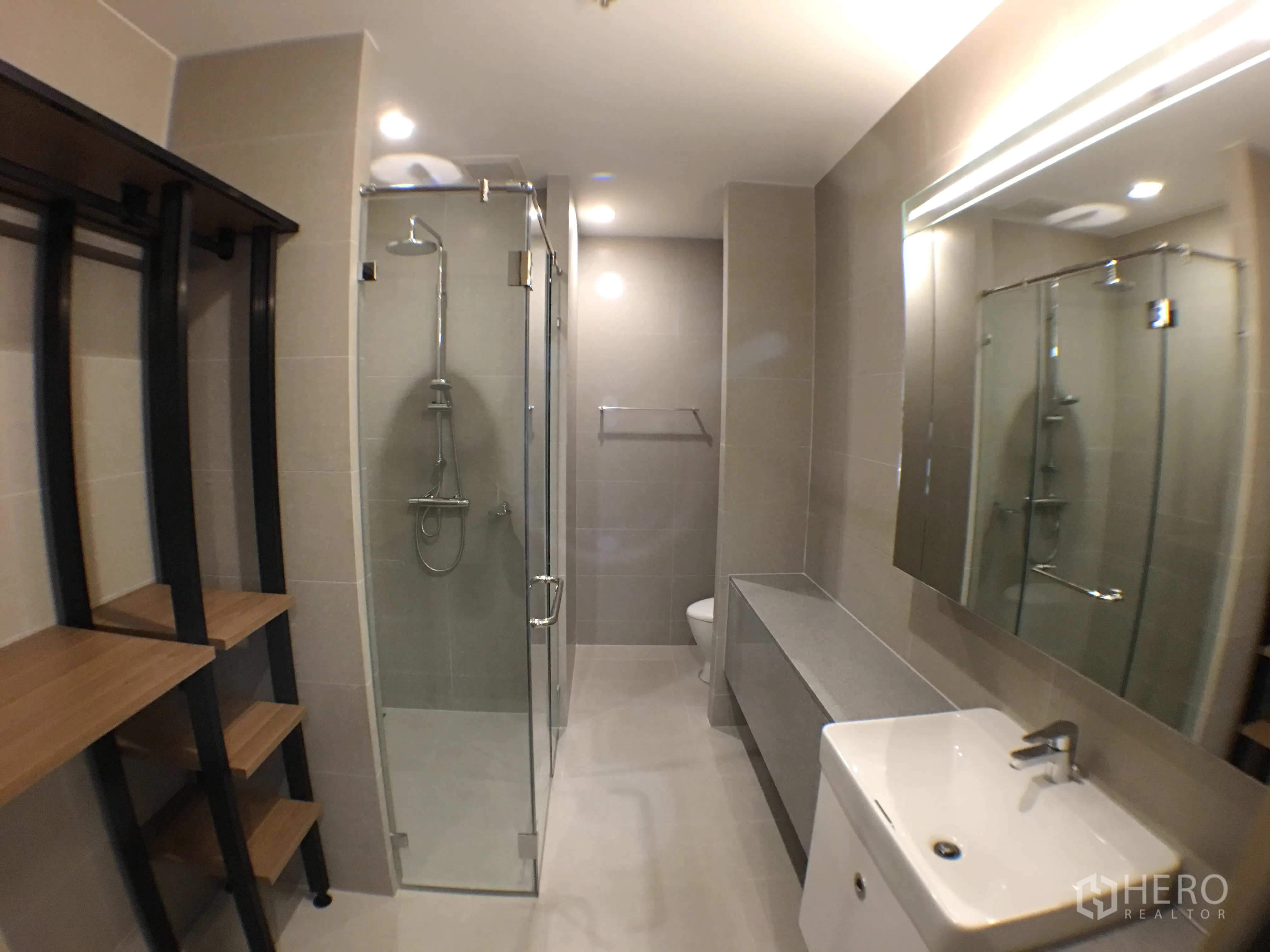 Condominium for rent in Pathum Wan, Bangkok - Modern bathroom with glass shower enclosure, vanity and large mirror.