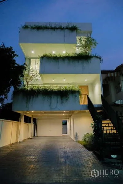 Home Office for rent in Phra Khanong, Bangkok - Evening exterior of the three-level home office with illuminated balconies and driveway.