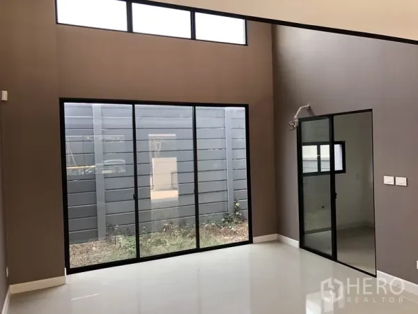 Townhouse for sale in Saphan Sung, Bangkok - Bright double-height living area with floor-to-ceiling sliding doors opening to a small courtyard.