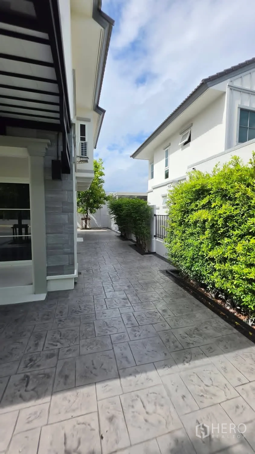 Detached House for rent in Bang Phli, Samut Prakan - Side terrace with gray tiles, green hedges, and neighboring modern homes.