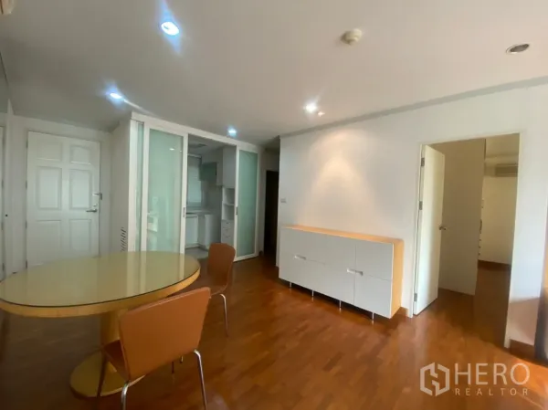 Condominium for rent or sale in Sathon, Bangkok - Dining nook with round table and chairs beside frosted glass doors to the kitchen.
