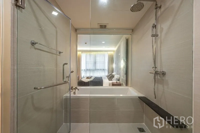 公寓 出售 - 现代浴室，玻璃淋浴区、浴缸与顶喷花洒。