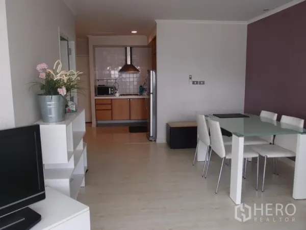 Condominium for rent in Sathon, Bangkok - Bright open-plan living and dining area with glass table, TV console, and a view toward the compact kitchen in a Sathon, Bangkok condo.