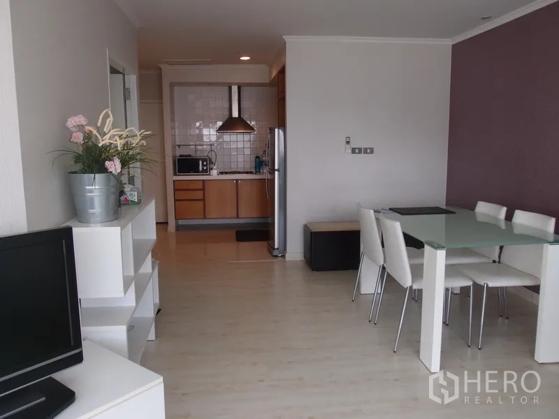 Condominium for rent in Sathon, Bangkok - Bright open-plan living and dining area with glass table, TV console, and a view toward the compact kitchen in a Sathon, Bangkok condo.