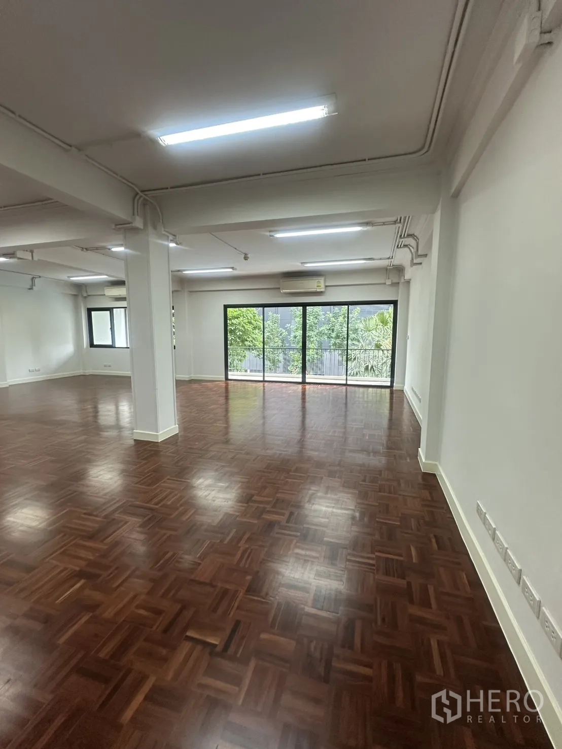 ออฟฟิศ for rent in Watthana, Bangkok - พื้นที่สำนักงานเปิดโล่ง พื้นไม้ปาร์เกต์เงางามและประตูกระจกบานเลื่อนออกสู่ระเบียงยาว