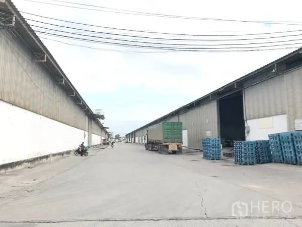 货栈 出租在Bang Sao Thong, Samut Prakan - 两侧大型金属仓库与宽阔通道，装卸区可供卡车进出。