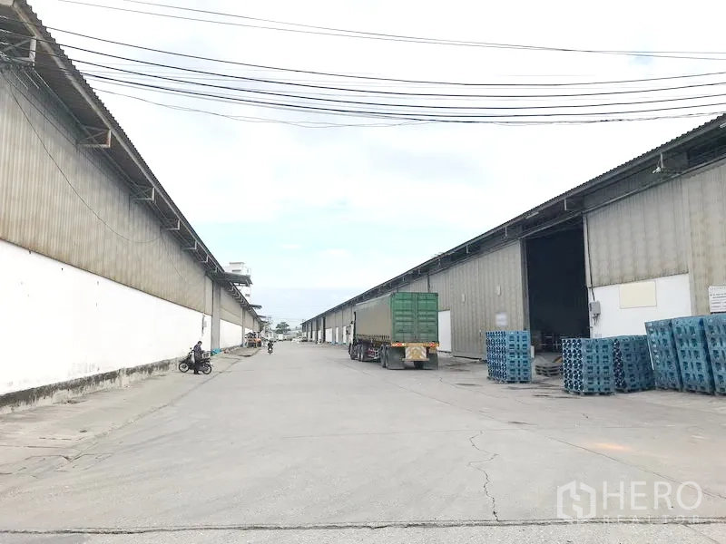 货栈 出租在Bang Sao Thong, Samut Prakan - 两侧大型金属仓库与宽阔通道，装卸区可供卡车进出。