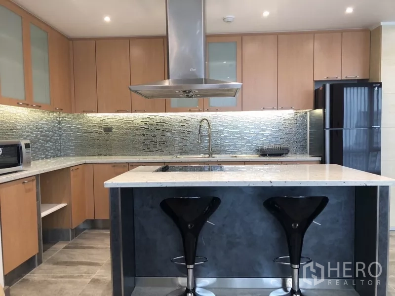 公寓 出租在Sathon, Bangkok - 厨房中岛与两把吧椅，对面为灶台与不锈钢烟机。