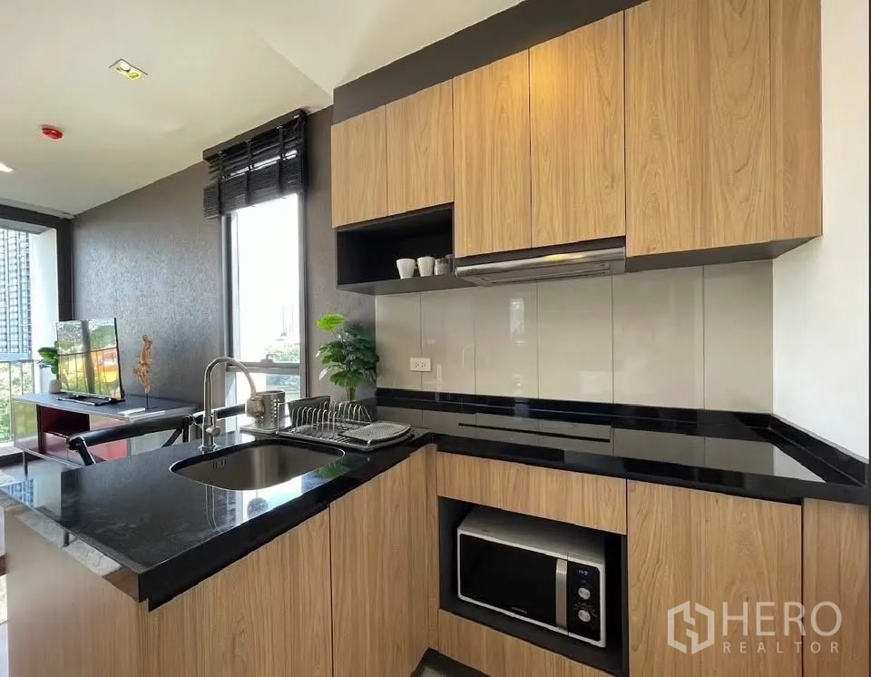 คอนโด for rent in Watthana, Bangkok - ภาพระยะใกล้ของครัวพร้อมอ่างล้างจาน ไมโครเวฟ และชั้นวางของติดกับพื้นที่นั่งเล่น