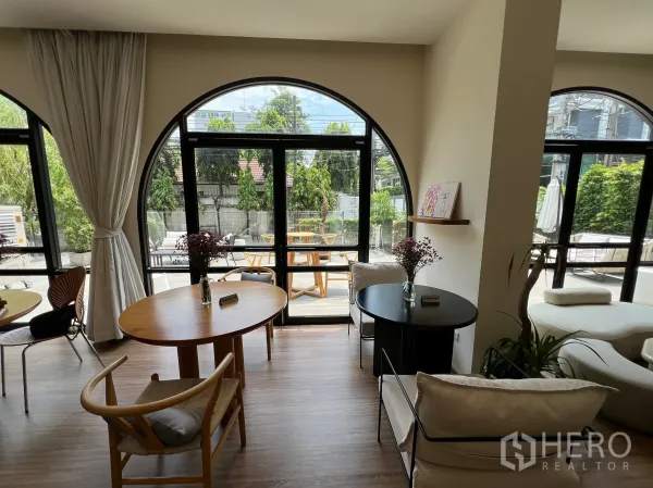 零售空间 出租在Watthana, Bangkok - 采光充足的室内，木地板与拱形窗，座位区可眺望露台景致。