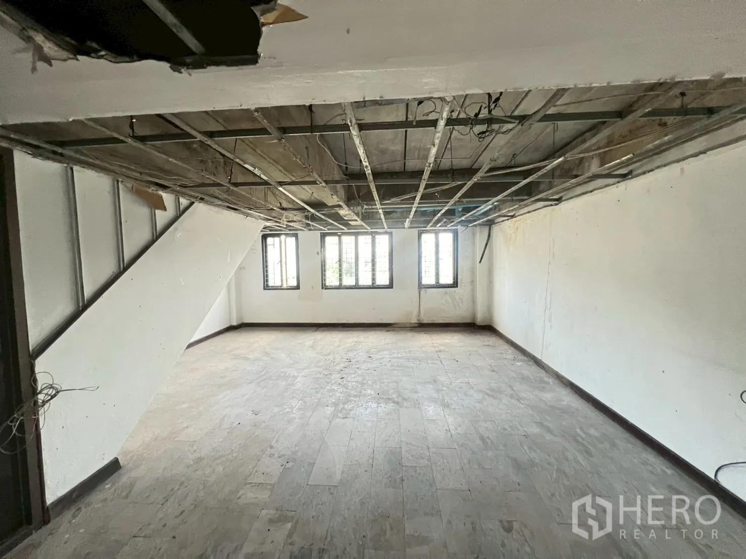 店屋 出租在Phra Khanong, Bangkok - 开放式楼层，裸露吊顶框架与三扇前窗。