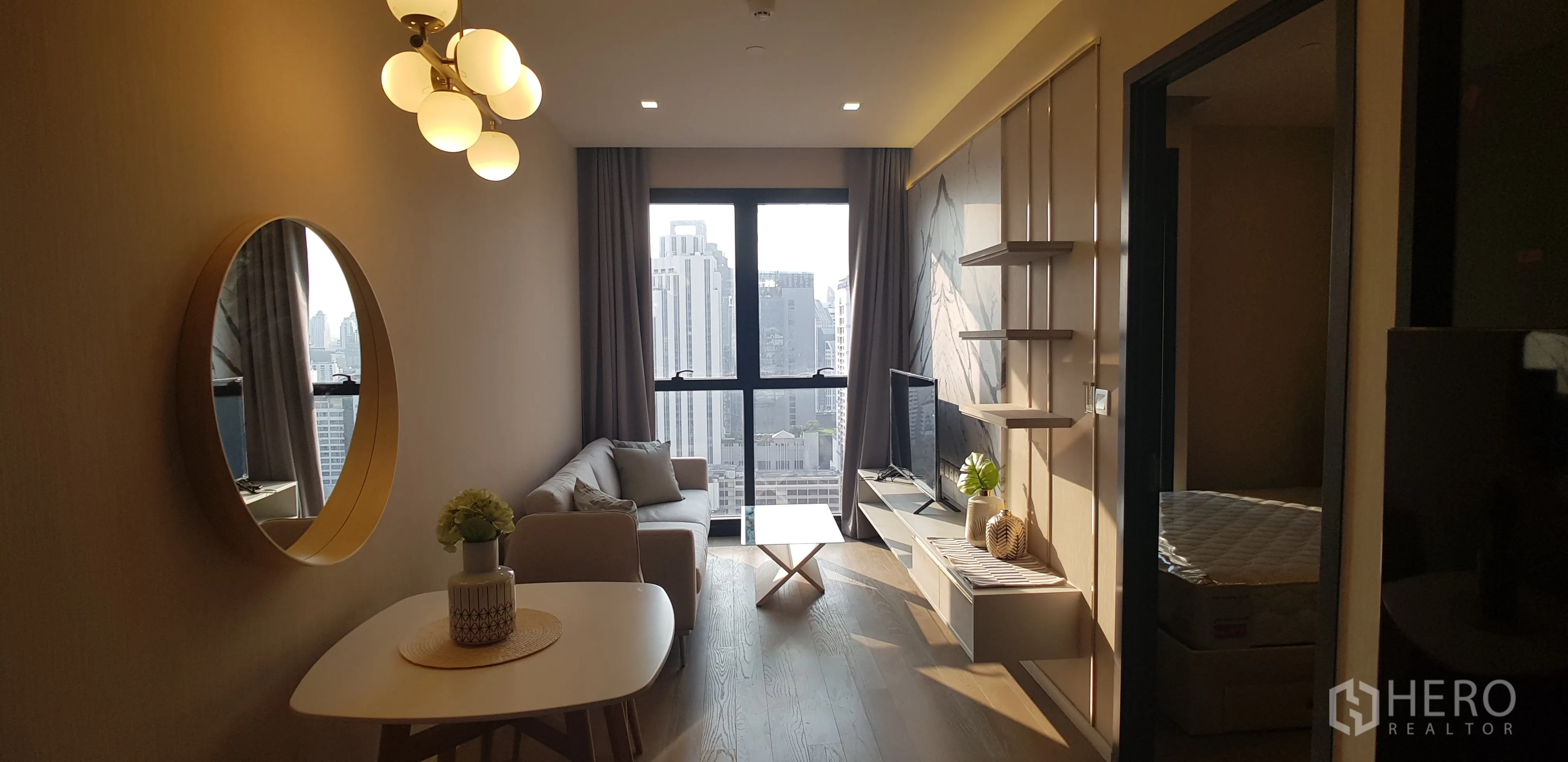 Condominium for rent in Watthana, Bangkok - Bright living room with sofa, TV wall and floor-to-ceiling windows overlooking the Bangkok skyline.