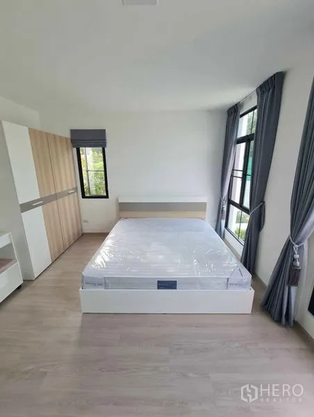 ทาวน์เฮาส์ ให้เช่าในBang Phli, Samut Prakan - ห้องนอนสว่าง เตียงคู่ ตู้เสื้อผ้า หน้าต่างบานใหญ่ ผ้าม่านสีเทา พื้นไม้