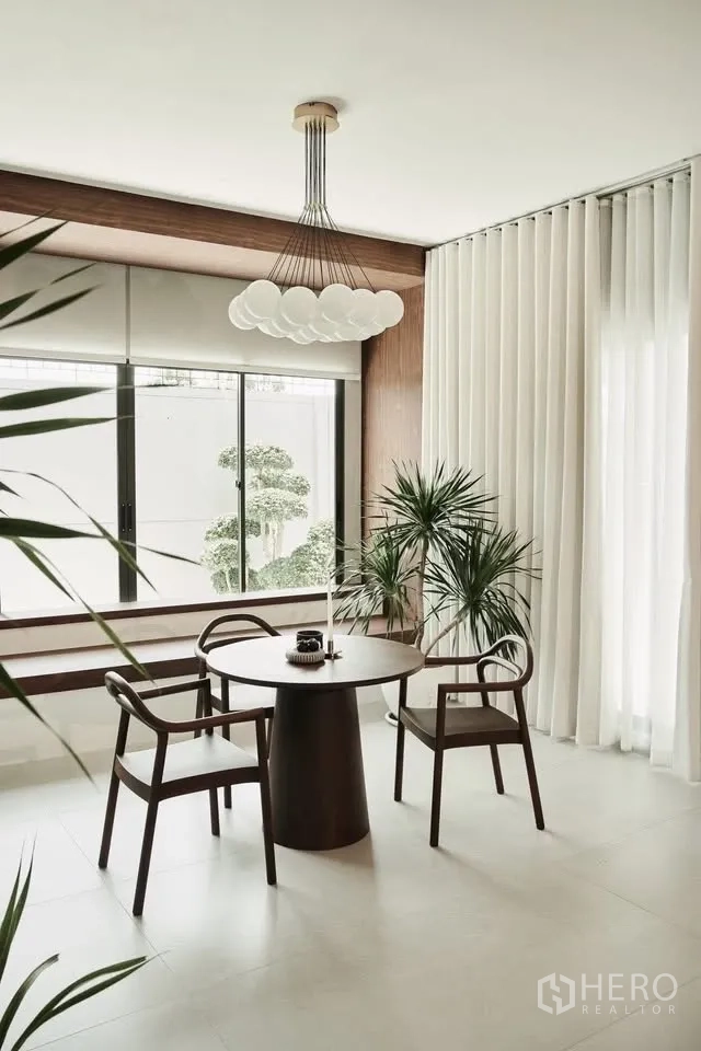Detached House for rent or sale in Lat Krabang, Bangkok - Bright breakfast nook with round table, three chairs, large windows, and indoor plants.