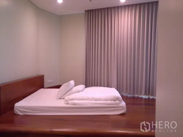 公寓 出租或出售在Khlong Toei, Bangkok - 温馨卧室，木质平台床、筒灯和落地窗帘。