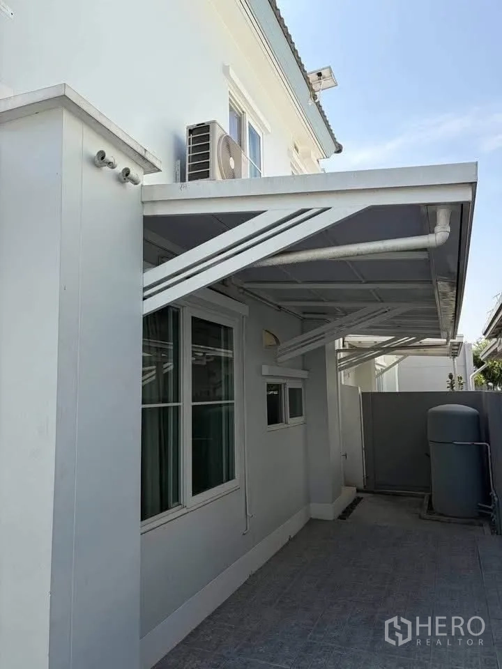 Semi-detached House for rent in Prawet, Bangkok - Covered side area with metal awning, air-conditioning unit, and utility tank.