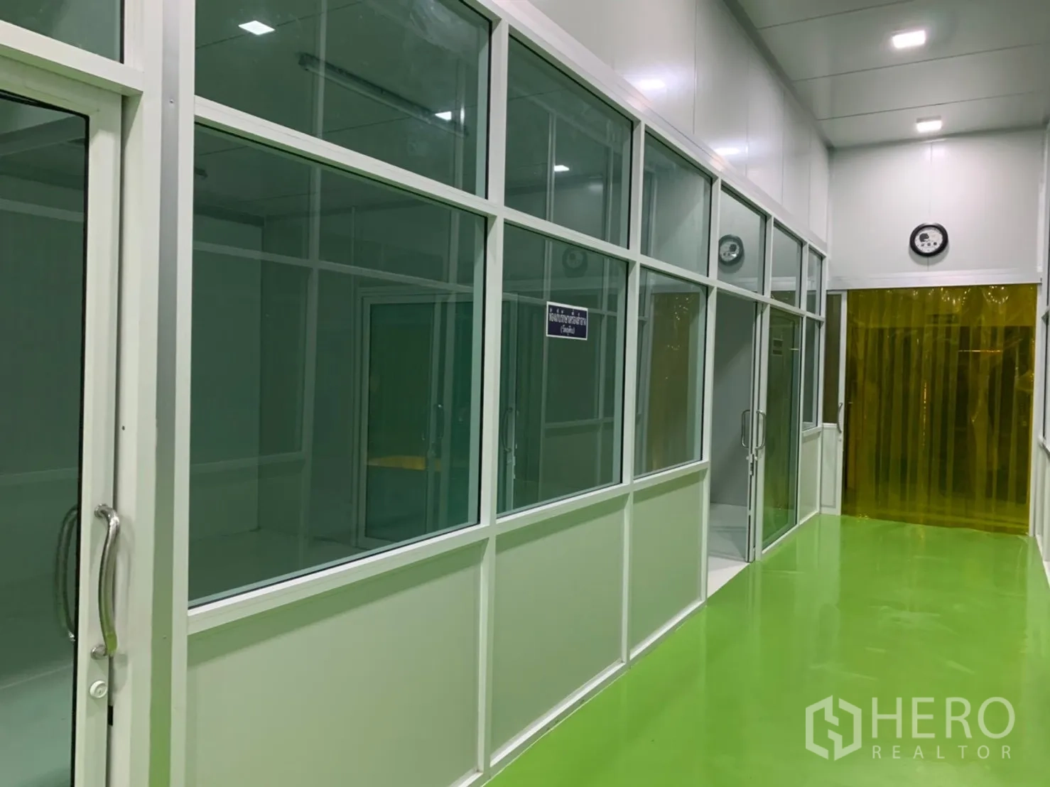 โรงงาน for rent in Khlong Luang, Pathum Thani - โถงทางเดินเรียงห้องกระจกตลอดแนว ไปยังประตูม่านสีเหลืองด้านท้าย