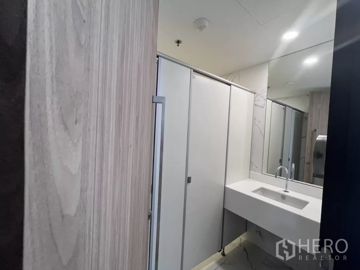办公空间 for rent in Din Daeng, Bangkok - 现代洗手间，白色隔间门、大镜子与一体式洗手台。