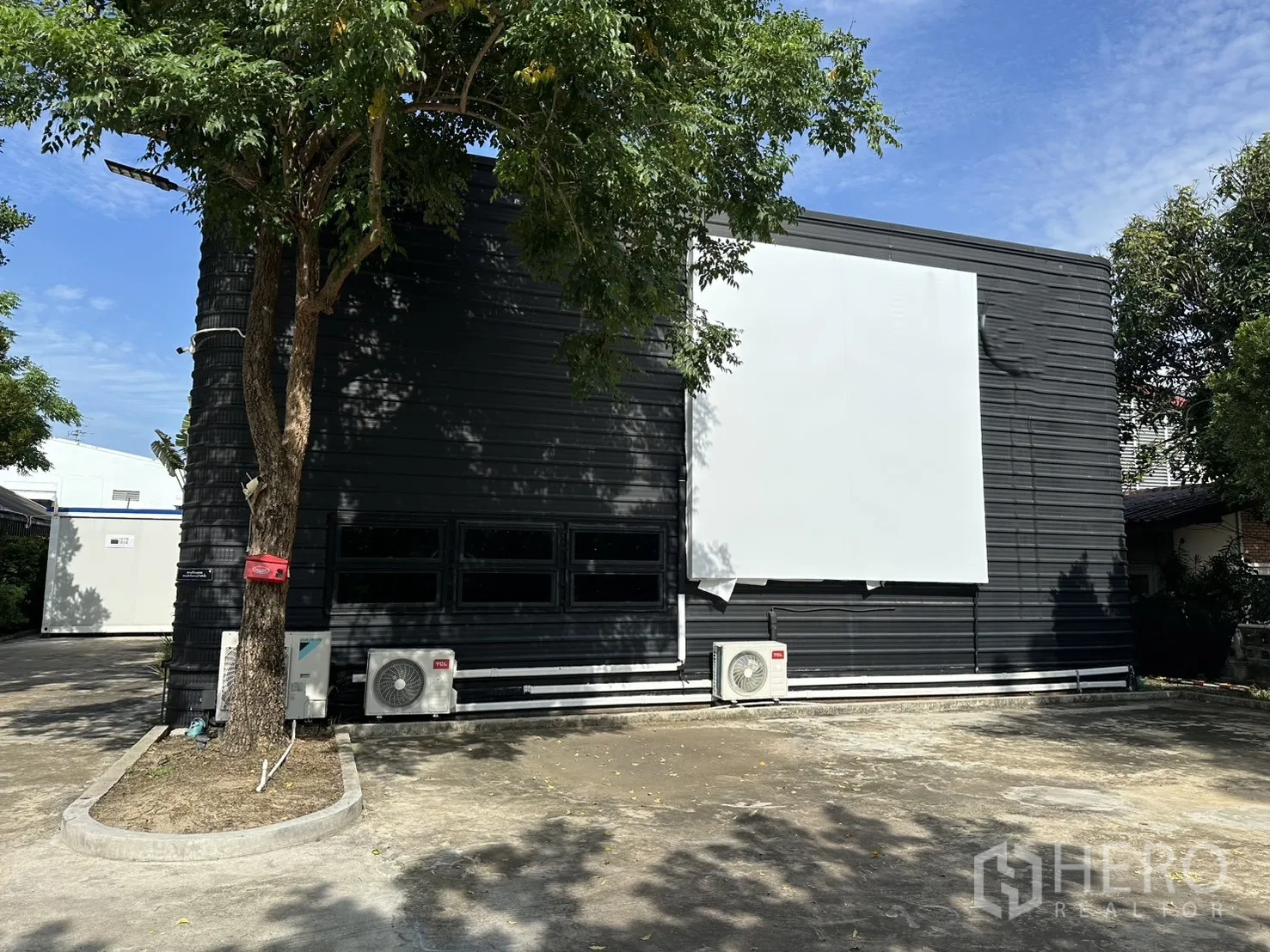 โกดัง for rent in Phra Khanong, Bangkok - ด้านหน้าอาคารโกดังพร้อมแผงติดป้ายขนาดใหญ่และพื้นที่จอดรถ