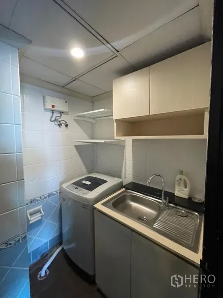 Condominium for sale in Chatuchak, Bangkok - Compact laundry room with washing machine, storage shelves and utility sink.