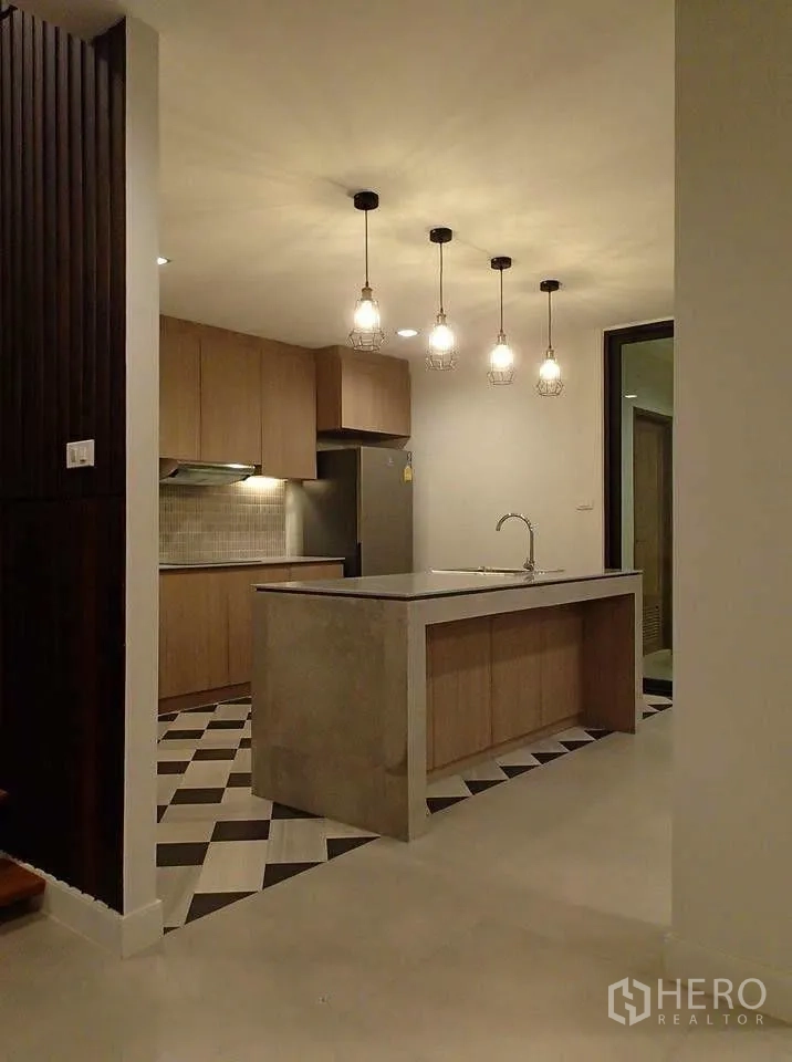Townhouse for rent in Watthana, Bangkok - Kitchen island with pendant lights, fridge, and tiled flooring.