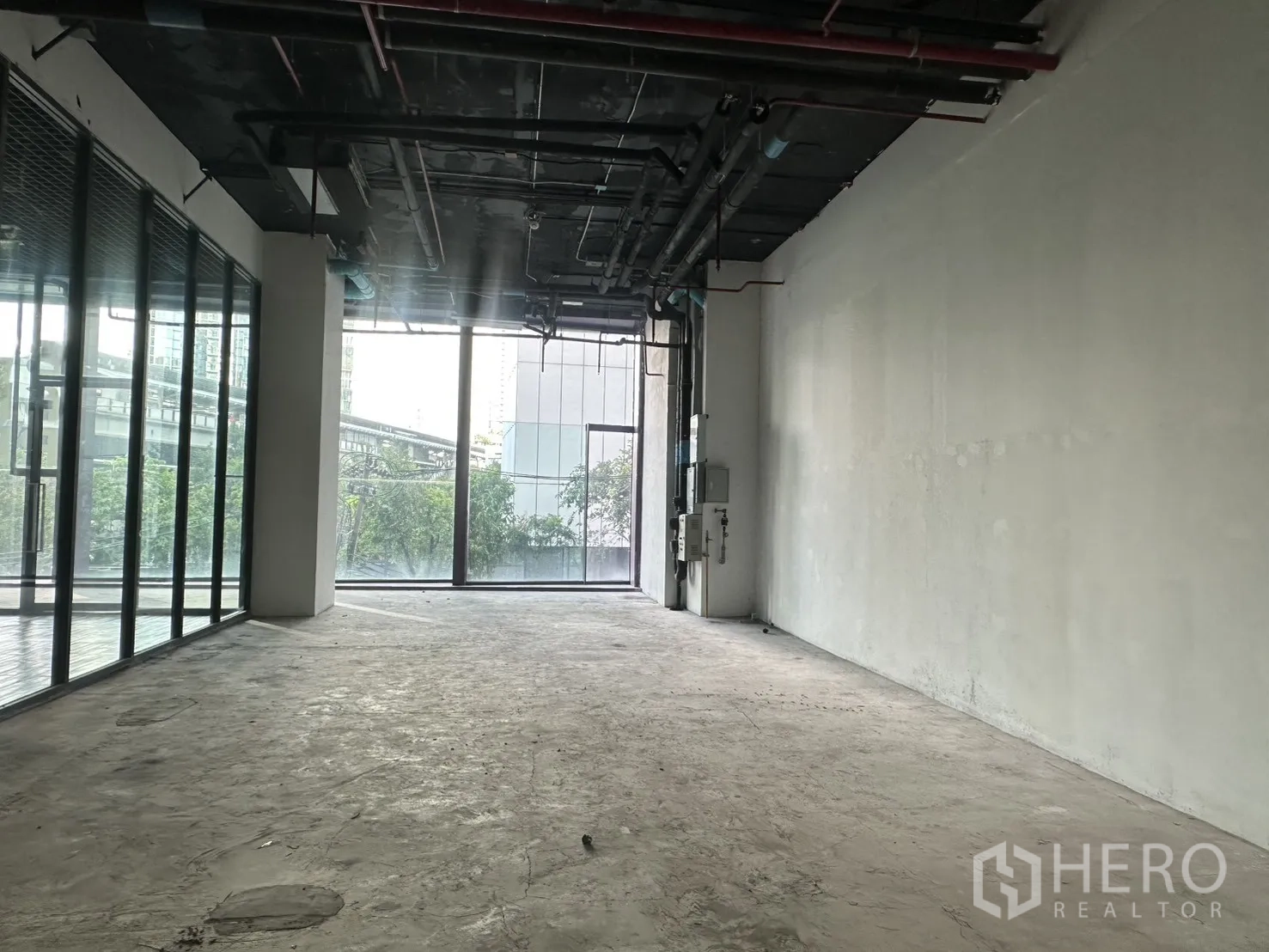 Retail Space for rent in Khlong Toei, Bangkok - Open shell retail unit with high exposed ceiling, concrete floor, and floor-to-ceiling windows.
