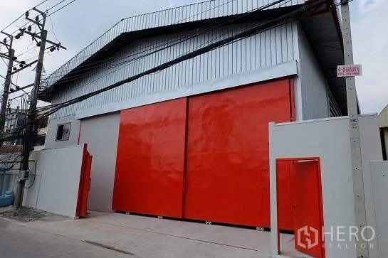 โกดัง for rent in Bang Phli, Samut Prakan - ทางเดินด้านข้างโกดังพร้อมประตูบานเลื่อนที่เปิดบางส่วน.