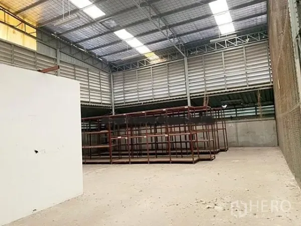 Warehouse for rent in Suan Luang, Bangkok - High-ceiling warehouse bay with metal roof, skylights, ventilation louvers and steel storage racks.